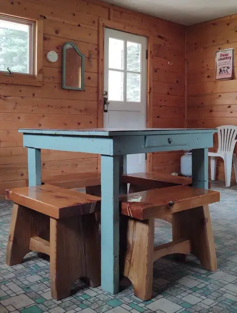 An interior view of a wooden cabin featuring a blue table and matching benches.