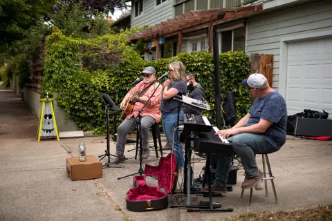 A band performs music outside in a driveway.