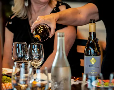 A person pouring wine into a glass from a bottle.