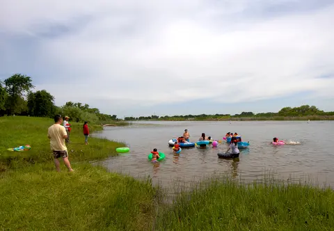 People enjoy tubing and swimming in a lake on a sunny day.