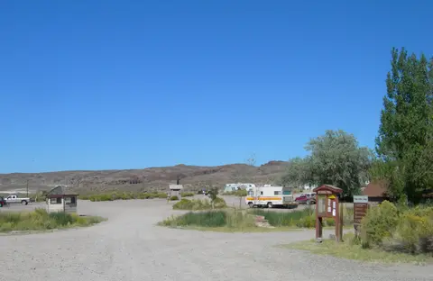 A dirt parking and camping area under a clear blue sky.