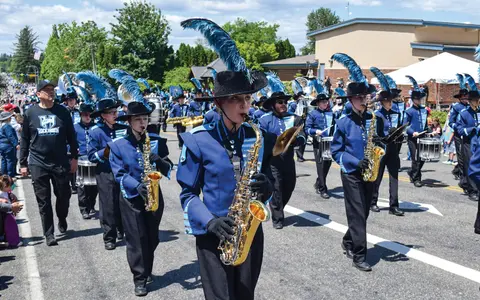 A marching band plays instruments in a street parade.