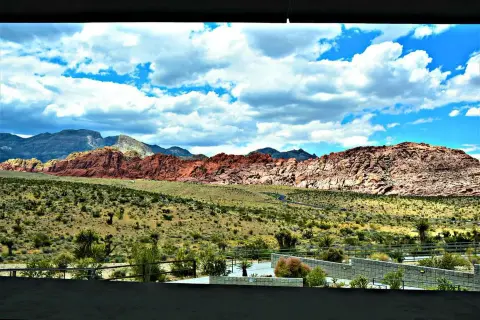 A scenic landscape view of mountains, desert terrain, and a cloudy blue sky.
