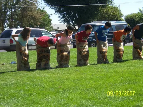 Children participating in a potato sack race on a lawn.