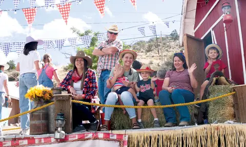 A group of people in western wear riding on a decorated float.