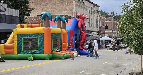 A street scene featuring large inflatable bounce houses during an outdoor community event.