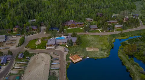 An aerial view shows a resort nestled among trees next to a body of water.