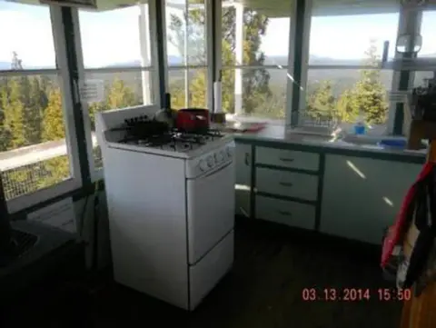 An interior view of a room with many windows and a kitchen stove.