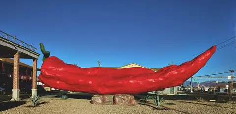 A giant red chili pepper sculpture outdoors.
