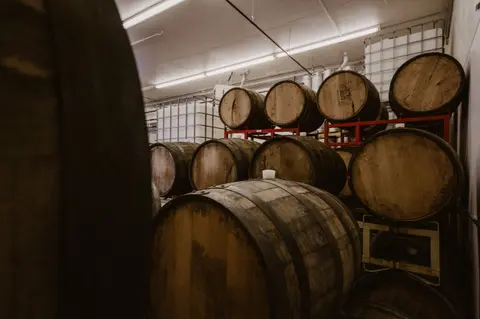 Wooden barrels are stacked in a cellar.