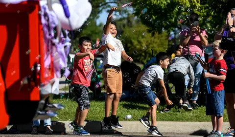 Children jump and play amidst bubbles during a parade.