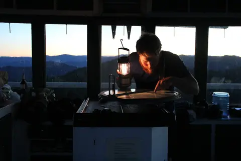 A man uses a lantern to look at a circular map inside a building.