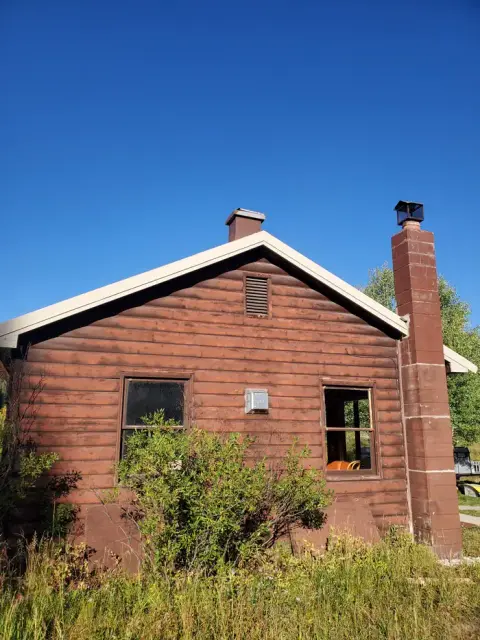 Exterior view of a rustic log cabin under a clear blue sky.
