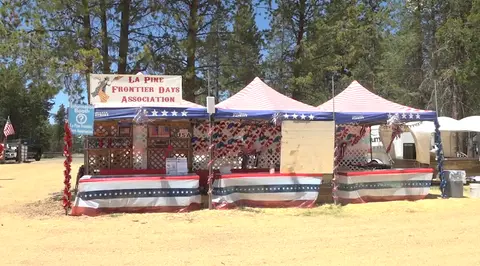 Outdoor booths decorated in patriotic colors with a banner for an association.