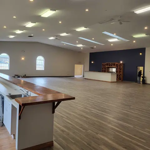An interior view of a large room with wooden floors, counters, and arched windows.