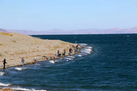 People fishing along the rocky shore of a lake.