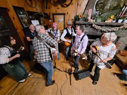 A group of people perform music inside a rustic room.
