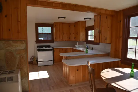An interior view of a rustic kitchen with wooden cabinets and paneling.