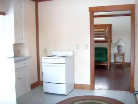 An interior view of a small kitchen with a white stove and a doorway leading to another room.