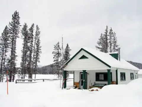 A snowy exterior view of a building surrounded by snow and trees.