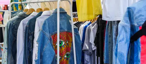 Clothing items hang on racks at a market or shop.