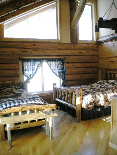 An interior shot of a bedroom with log cabin walls and two beds.