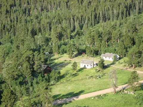An aerial view of several buildings nestled in a clearing surrounded by a dense forest.