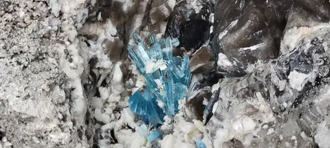 A close-up photograph of blue crystal minerals embedded in rock.