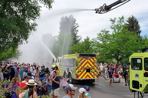 A fire truck sprays water over a crowd gathered on a street.