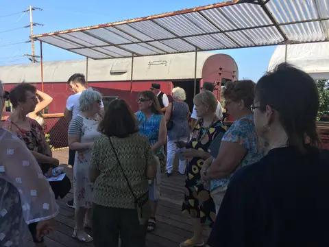 A group of people stand on a platform near a train car under a shelter.