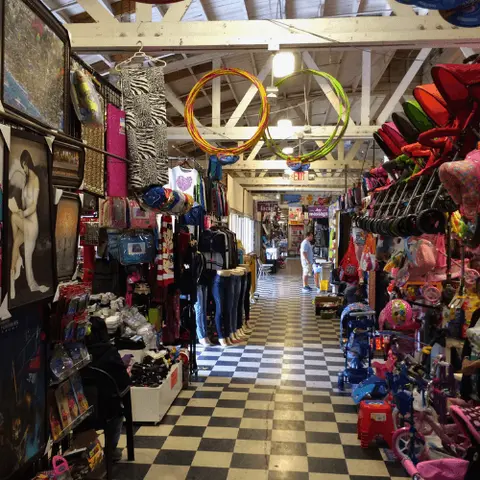 This photo shows the interior aisle of a store with a checkered floor and various goods on display.