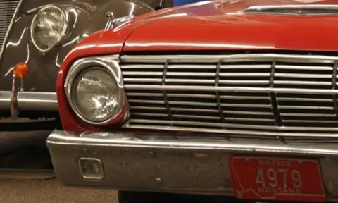 A close-up view of the front end of a vintage red car.
