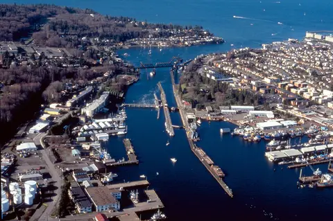 An aerial view shows a waterway with locks, bridges, and surrounding buildings.