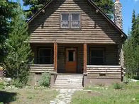 A log cabin stands among trees.
