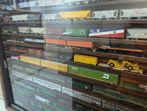 A display case filled with model trains and railroad cars on multiple shelves.