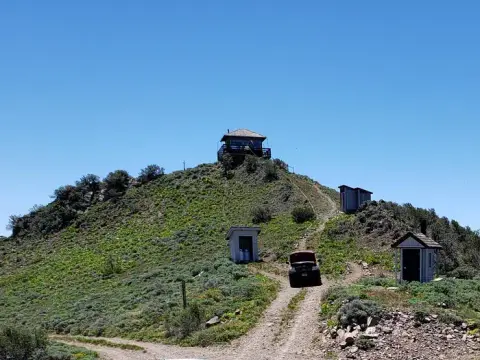 A dirt road leads up a grassy hill to a building on top.
