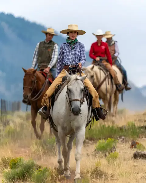 A group of people riding horses outdoors.