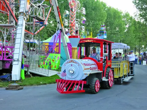 A train-styled ride vehicle drives past amusement park attractions.