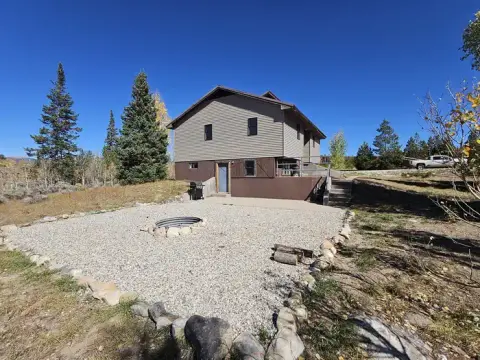 Exterior of a two-story building with a gravel patio and fire pit in the foreground.