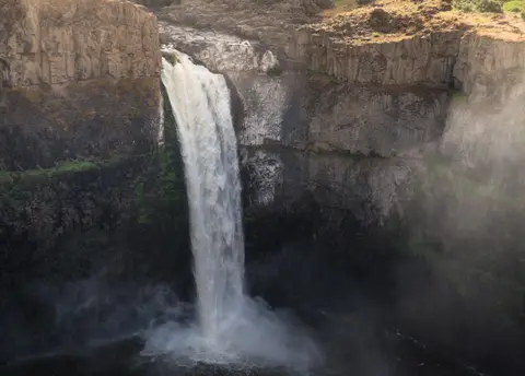 A tall waterfall plunges between rocky cliffs.