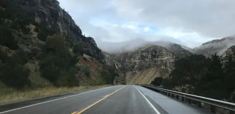 A wet highway winding through a mountainous landscape.