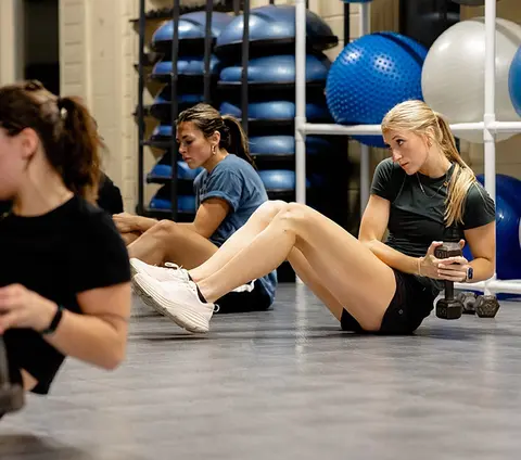 People exercising in a gym with weights and fitness balls.