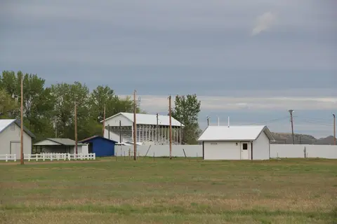 An outdoor view of buildings and a covered grandstand across a grassy field.