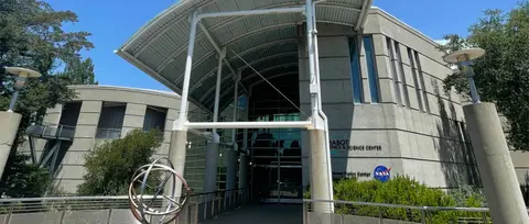 An exterior view of a modern building with a large curved roof over the entrance.