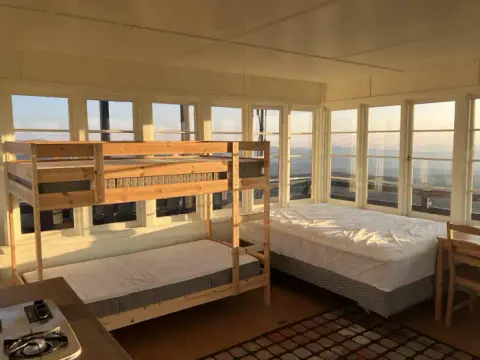 An interior view of a cabin with bunk beds and panoramic windows.
