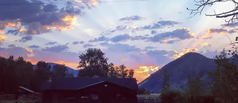 A scenic view of a sunset over mountains with a building in the foreground.