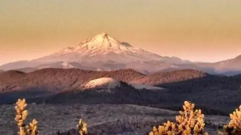 A scenic view of a snow-capped mountain range at sunset.