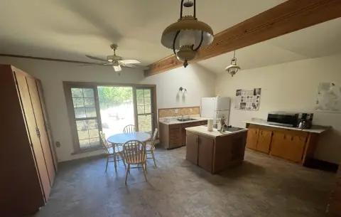 An interior shot of a rustic kitchen with a dining table and wooden cabinets.