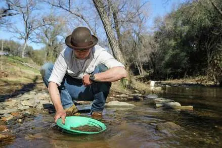 A person panning for gold in a stream.