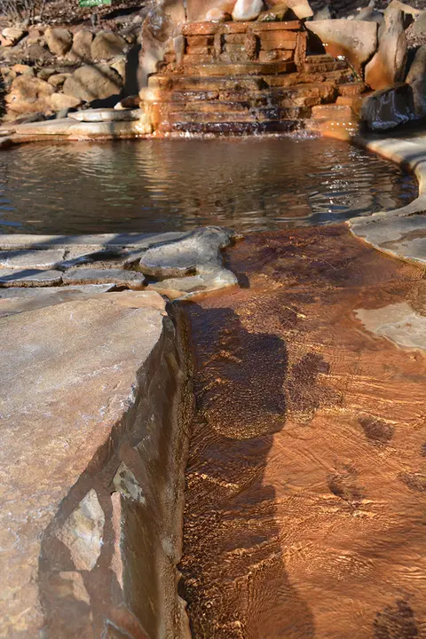 A stone pool and cascading water feature outdoors.